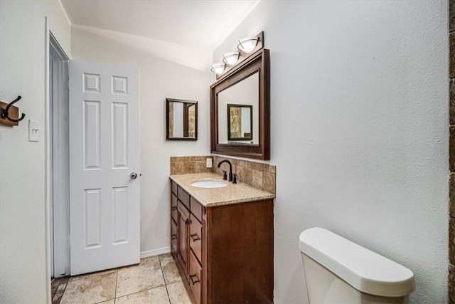 bathroom with tile patterned flooring, vanity, decorative backsplash, vaulted ceiling, and toilet