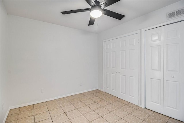 unfurnished bedroom featuring multiple closets, ceiling fan, and light tile patterned floors