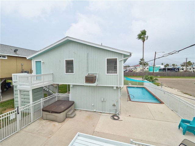 rear view of property featuring a swimming pool with hot tub and a patio