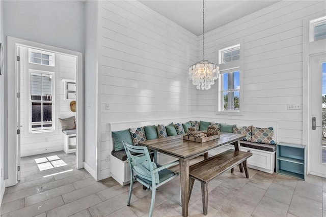 dining room with wood walls, breakfast area, and a notable chandelier