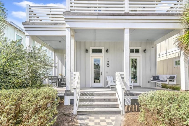 view of exterior entry featuring a porch, board and batten siding, and a balcony