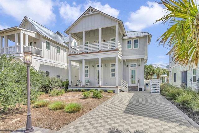 raised beach house featuring covered porch, board and batten siding, a standing seam roof, metal roof, and a balcony