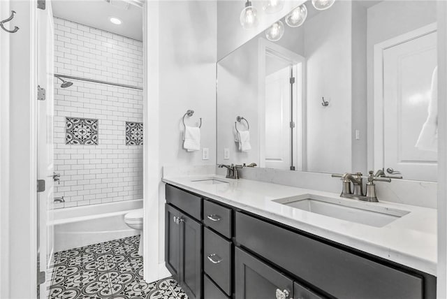 bathroom featuring toilet, double vanity, a sink, and tile patterned floors