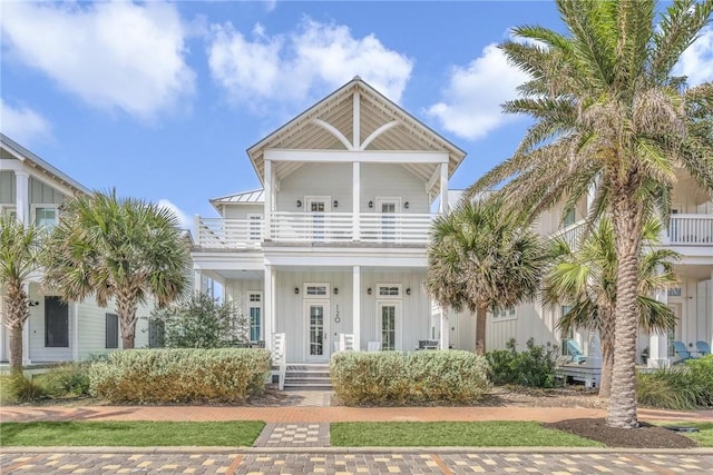 view of front of home with metal roof, a porch, a balcony, board and batten siding, and a standing seam roof