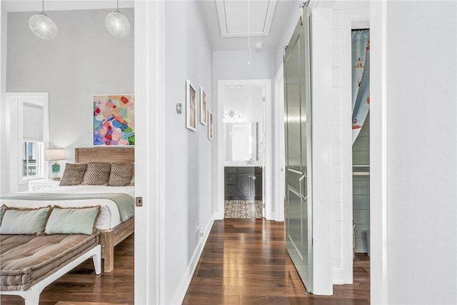 hall with attic access, dark wood finished floors, and baseboards