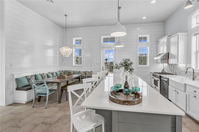 kitchen with stainless steel gas stove, dishwasher, breakfast area, under cabinet range hood, and a sink