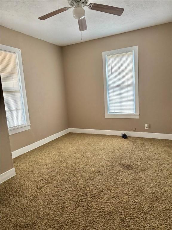 carpeted spare room featuring ceiling fan and a healthy amount of sunlight