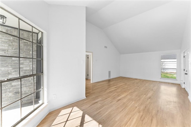 additional living space with light wood-type flooring, baseboards, high vaulted ceiling, and visible vents