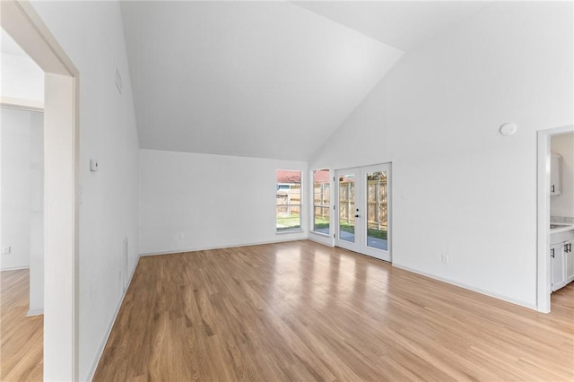 bonus room with baseboards, french doors, light wood-type flooring, and high vaulted ceiling