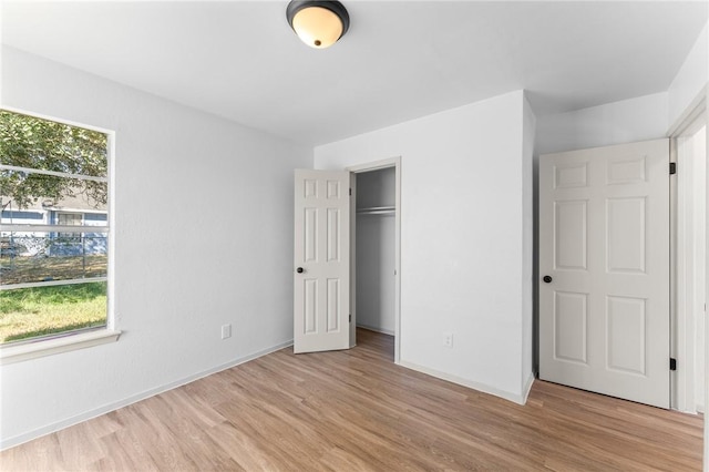 unfurnished bedroom with light wood-style floors, baseboards, and a closet