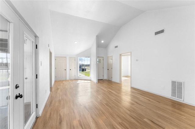 interior space with baseboards, visible vents, light wood finished floors, and high vaulted ceiling