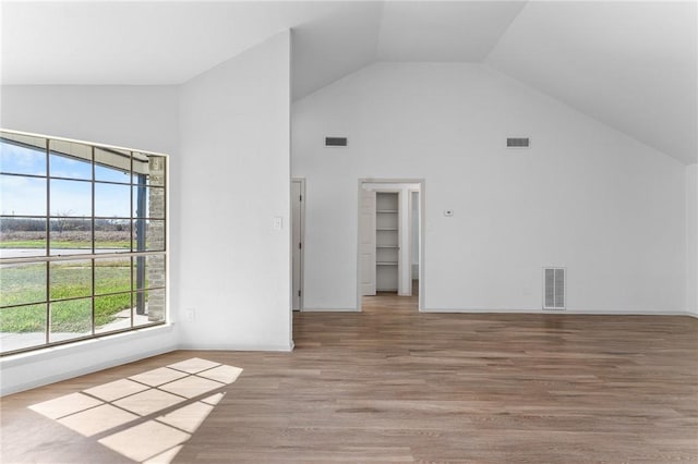 unfurnished room featuring visible vents, light wood finished floors, and high vaulted ceiling