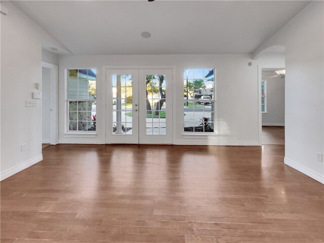 empty room with hardwood / wood-style floors, a wealth of natural light, and french doors