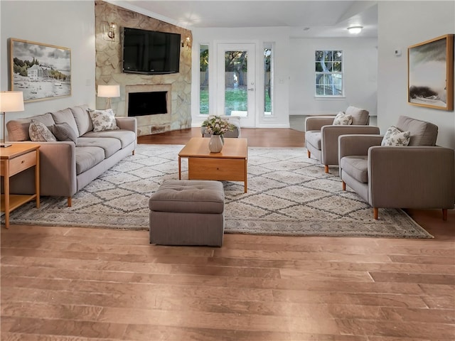 living room with a stone fireplace and light hardwood / wood-style flooring