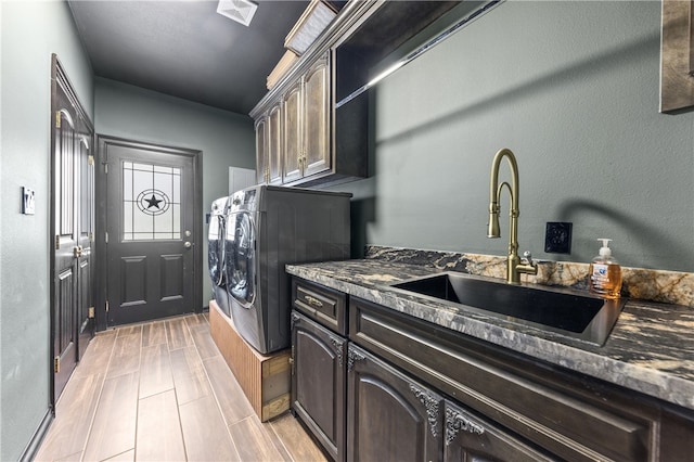 laundry area featuring light hardwood / wood-style floors, washer and clothes dryer, cabinets, and sink