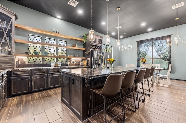 kitchen featuring hardwood / wood-style floors, pendant lighting, a center island with sink, and a breakfast bar area