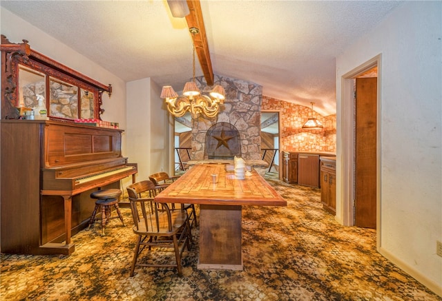 dining room with lofted ceiling with beams, a stone fireplace, a chandelier, and a textured ceiling