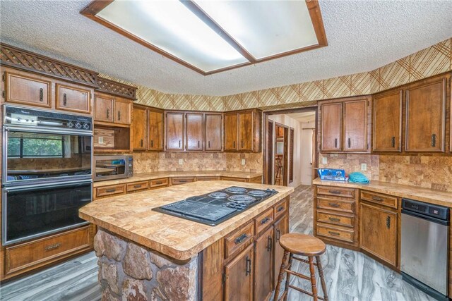 5490 County Road 73, Robstown, TX 78380 - kitchen with black appliances, a textured ceiling, light countertops, a kitchen island, and brown cabinets