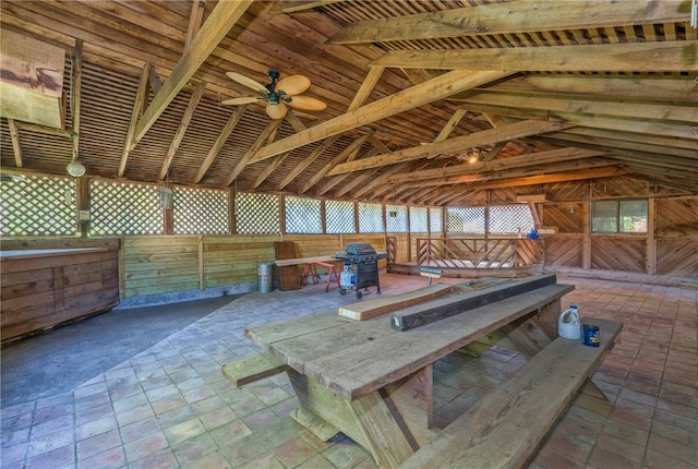 interior space featuring wood walls, ceiling fan, and vaulted ceiling