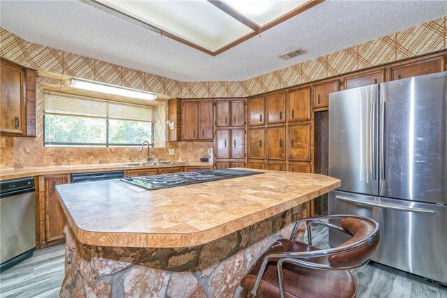 5490 County Road 73, Robstown, TX 78380 - kitchen with freestanding refrigerator, a sink, stovetop with downdraft, brown cabinetry, and light wood-style floors