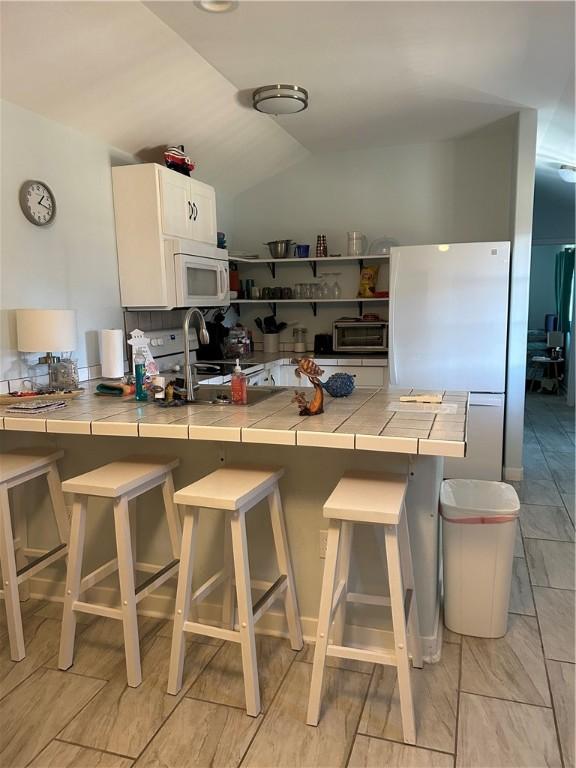 19 Estates Dr, Rockport, TX 78382 - kitchen with electric range oven, white microwave, tile countertops, a peninsula, and freestanding refrigerator
