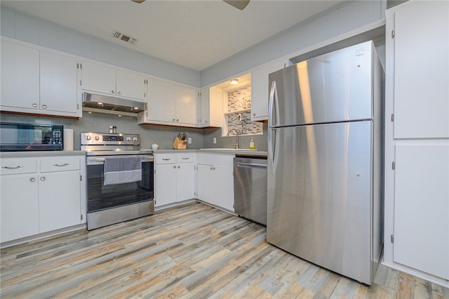 kitchen with light hardwood / wood-style floors, crown molding, white cabinetry, and appliances with stainless steel finishes