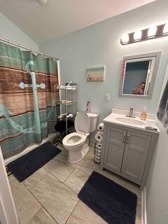 bathroom featuring walk in shower, vanity, vaulted ceiling, tile patterned flooring, and toilet