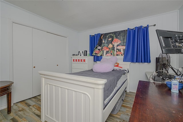 bedroom with wood walls, wood-type flooring, and crown molding