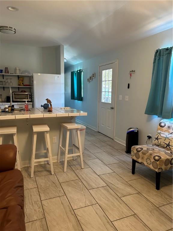 19 Estates Dr, Rockport, TX 78382 - kitchen featuring tile counters, freestanding refrigerator, and a breakfast bar