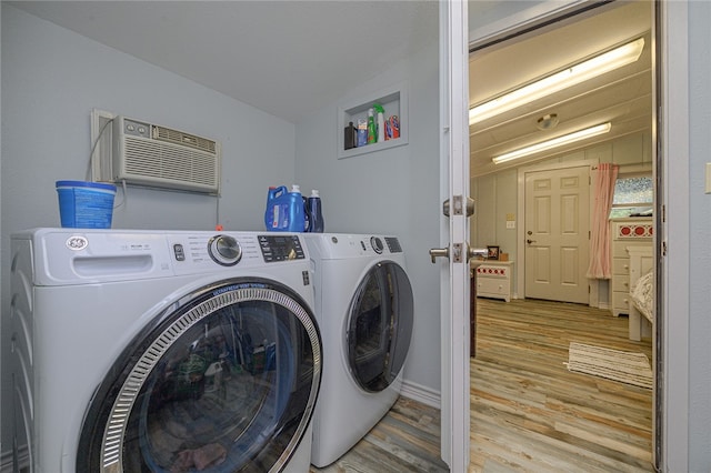 washroom featuring a wall unit AC, light hardwood / wood-style floors, and washing machine and clothes dryer