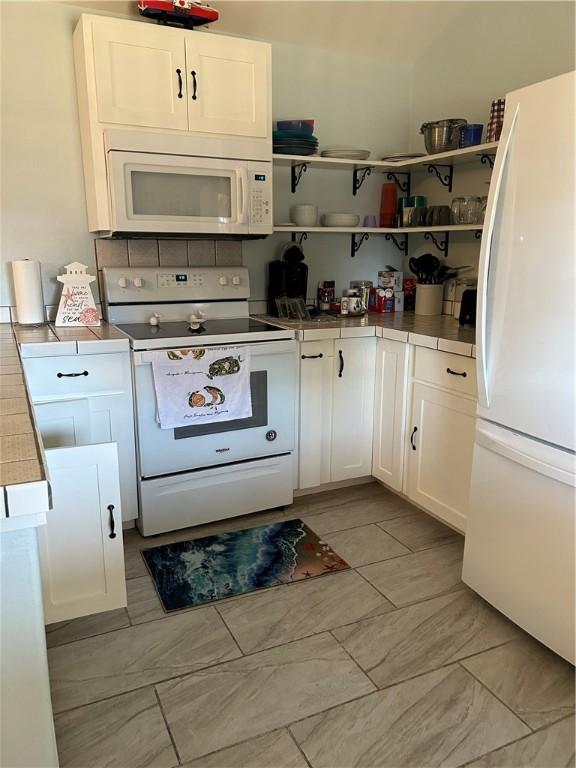 19 Estates Dr, Rockport, TX 78382 - kitchen featuring white appliances, white cabinetry, light marble finish flooring, and open shelves