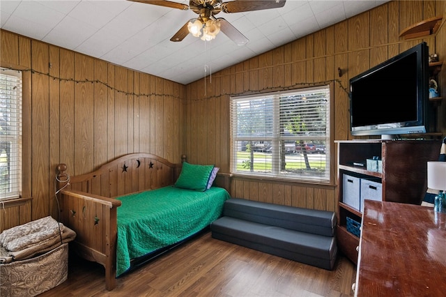 bedroom featuring wooden walls, vaulted ceiling, hardwood / wood-style flooring, and ceiling fan