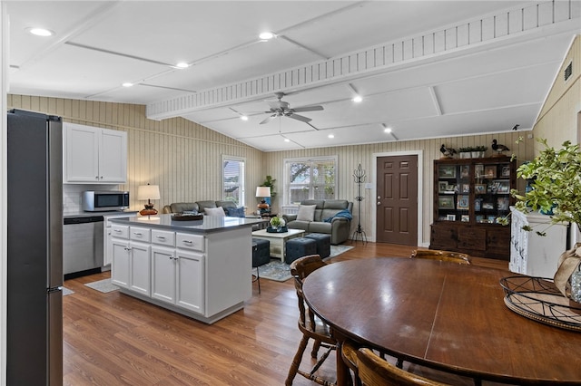 kitchen featuring white cabinets, stainless steel appliances, wood-type flooring, and a center island