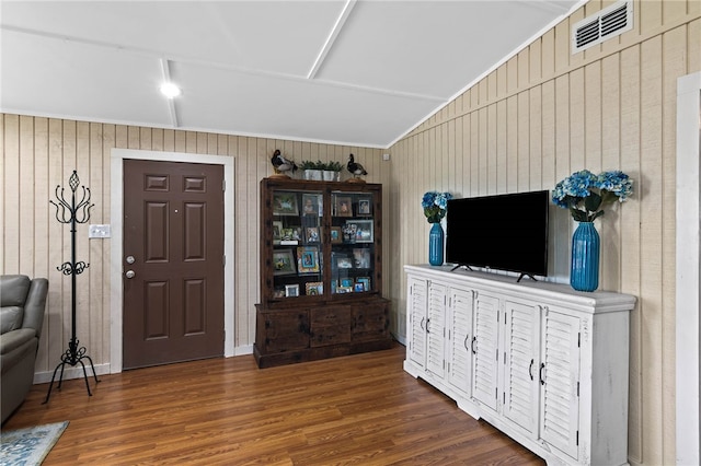 interior space featuring dark wood-type flooring, wooden walls, and vaulted ceiling