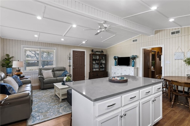 kitchen with white cabinetry, dark hardwood / wood-style flooring, wood walls, and a kitchen island