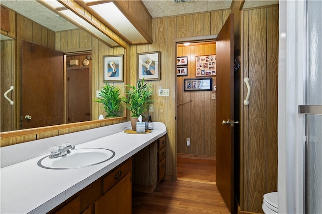 bathroom featuring vanity, hardwood / wood-style flooring, and wooden walls