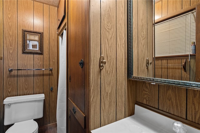 bathroom featuring wooden walls and toilet