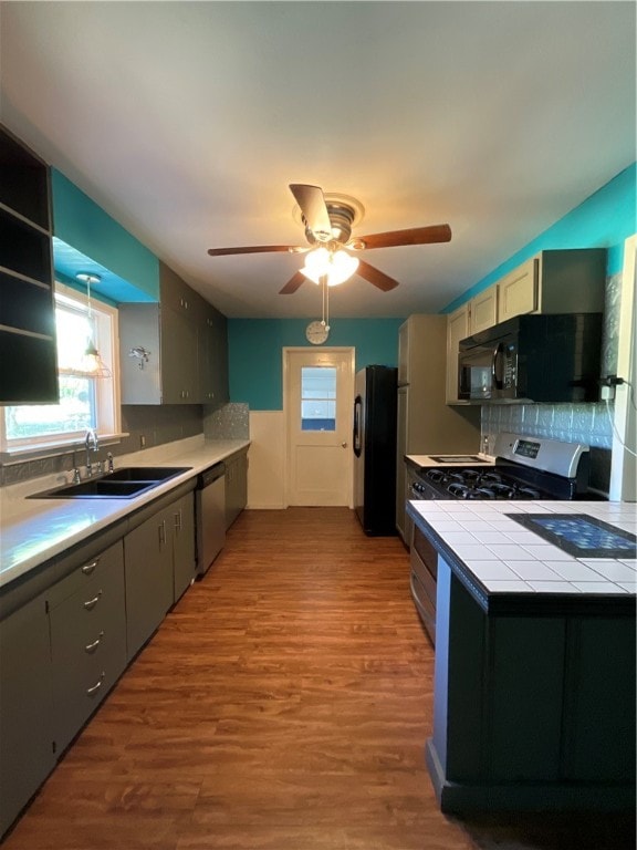 kitchen featuring sink, black appliances, backsplash, tile counters, and light wood-type flooring