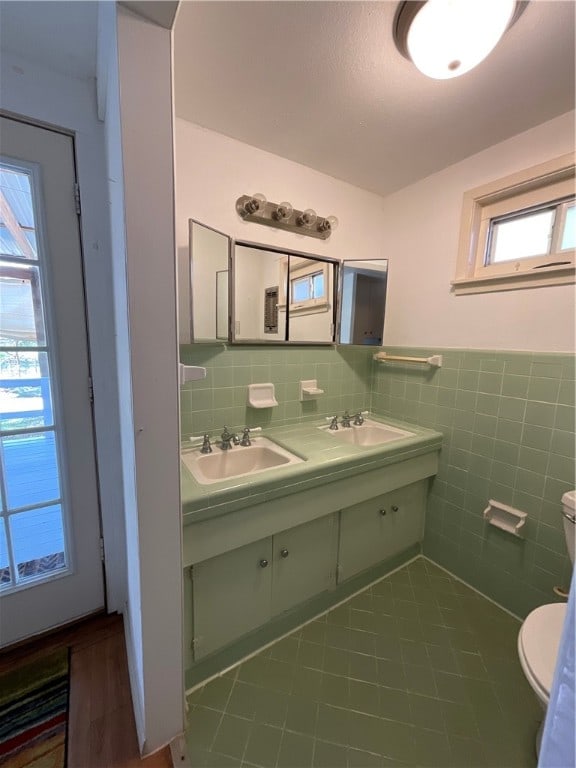 bathroom with toilet, vanity, tile patterned flooring, and tile walls