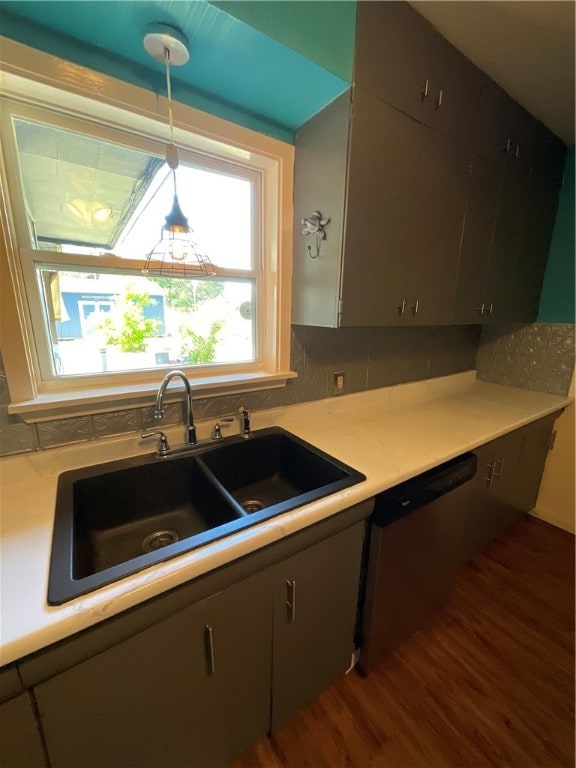 kitchen featuring decorative backsplash, hanging light fixtures, sink, stainless steel dishwasher, and dark hardwood / wood-style floors