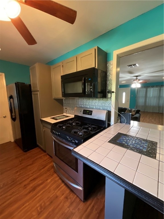 kitchen featuring tile counters, black appliances, decorative backsplash, and hardwood / wood-style flooring