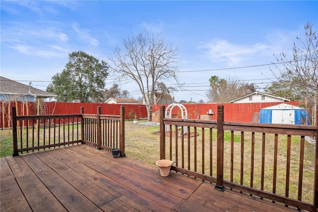 wooden terrace featuring a storage unit and a lawn