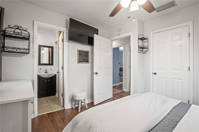 bedroom with dark hardwood / wood-style flooring, connected bathroom, sink, and ceiling fan