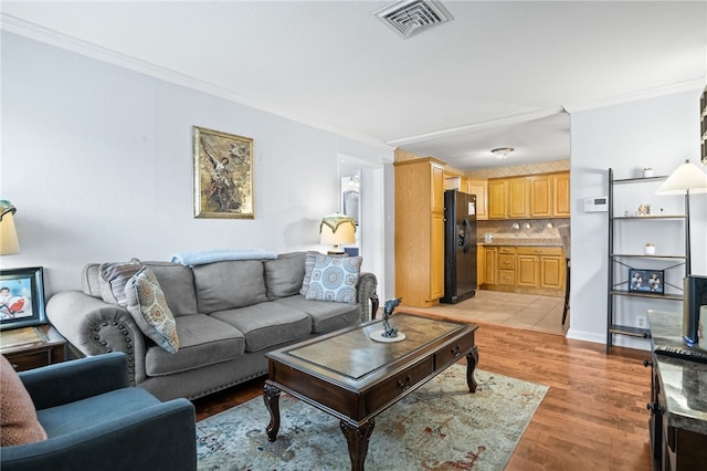 living room with ornamental molding and light hardwood / wood-style floors