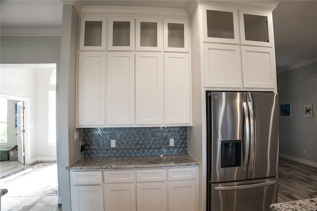 kitchen with stainless steel fridge with ice dispenser, crown molding, white cabinets, and light stone counters