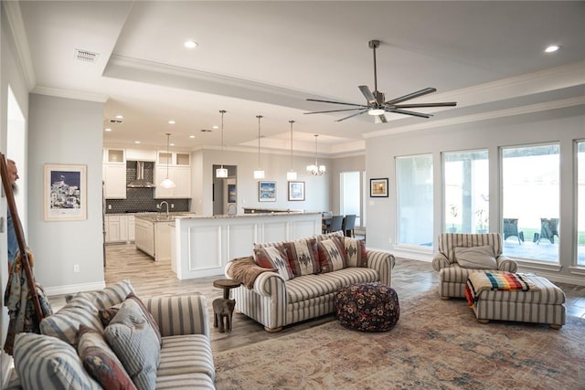 living room featuring plenty of natural light, sink, and a tray ceiling