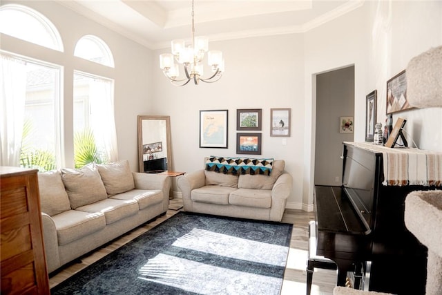 living room with a raised ceiling, ornamental molding, a chandelier, and hardwood / wood-style floors