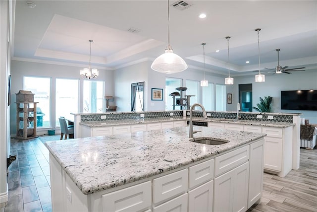 kitchen with sink, a tray ceiling, and a large island