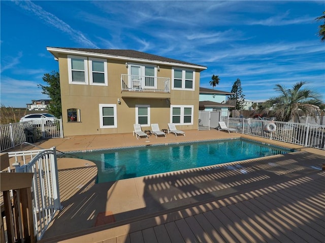 back of house featuring a fenced in pool, a balcony, and a patio area