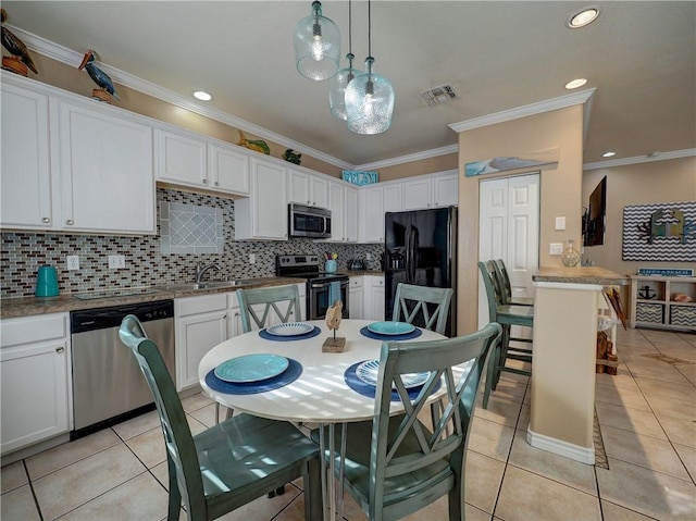 kitchen with light tile patterned flooring, appliances with stainless steel finishes, decorative light fixtures, and white cabinets